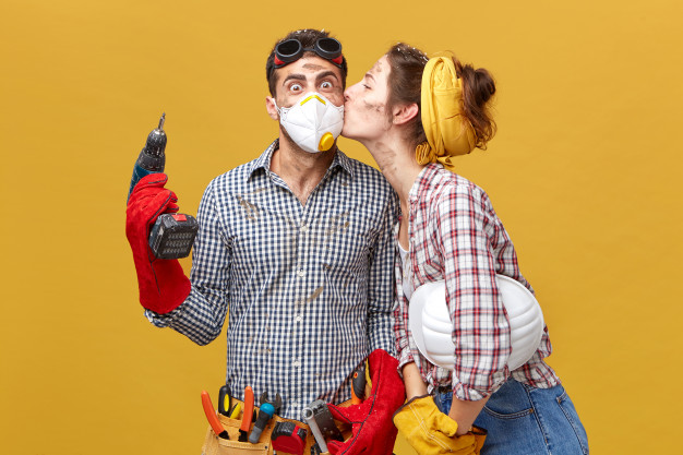 pretty-female-kissing-her-husband-cheek-being-thankful-him-repairing-her-wardrobe-surprised-male-worker-mask-holding-drilling-machine-being-glad-receive-kiss-from-his-girl